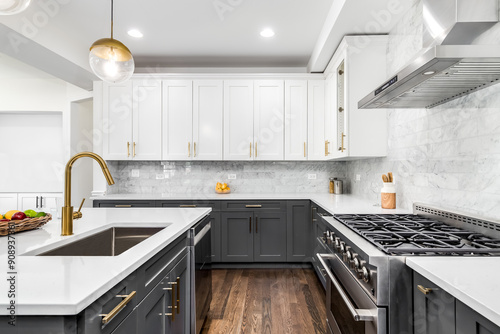 A luxurious white and grey kitchen with gold hardware, stainless steel appliances, and white marbled granite countertops. No brands or labels.