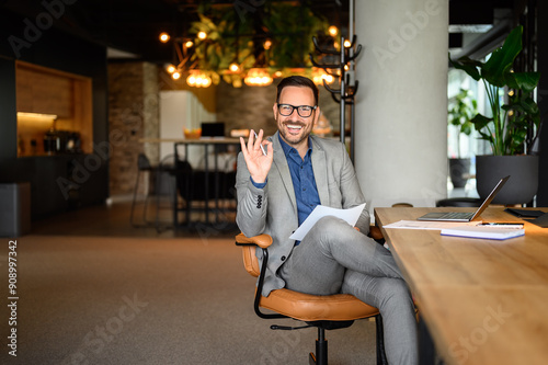 Obraz na plátně Portrait of smiling male entrepreneur with report showing OK sign while working