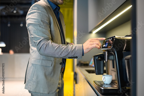 Midsection of male project manager preparing coffee with coffeemaker while working in modern office