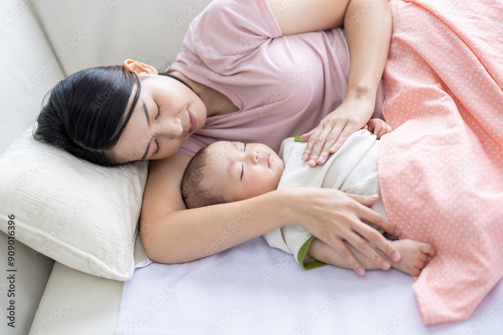 Asian woman lying with baby boy on the bed holding his little fingers. Happy baby boy was holding by his mother. Asian family with little boy at home enjoy tender family moment, motherhood. Asian woman lying with baby boy on the bed holding his little fingers. Happy baby boy was holding by his mother. Asian family with little boy at home enjoy tender family moment, motherhood.