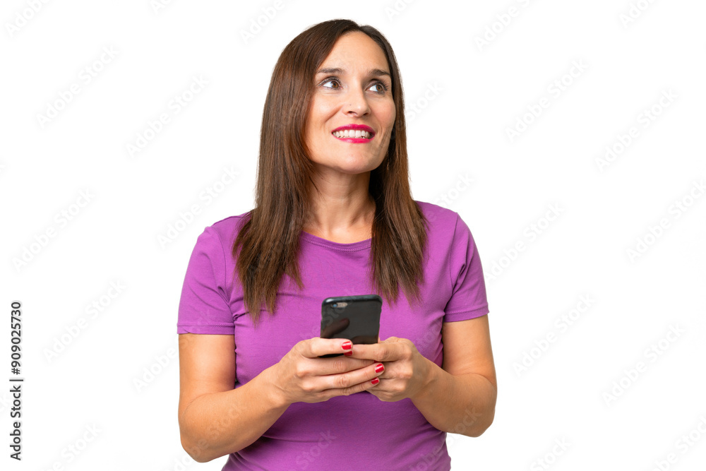 Middle-aged caucasian woman over isolated background using mobile phone and looking up Middle-aged caucasian woman over isolated background using mobile phone and looking up