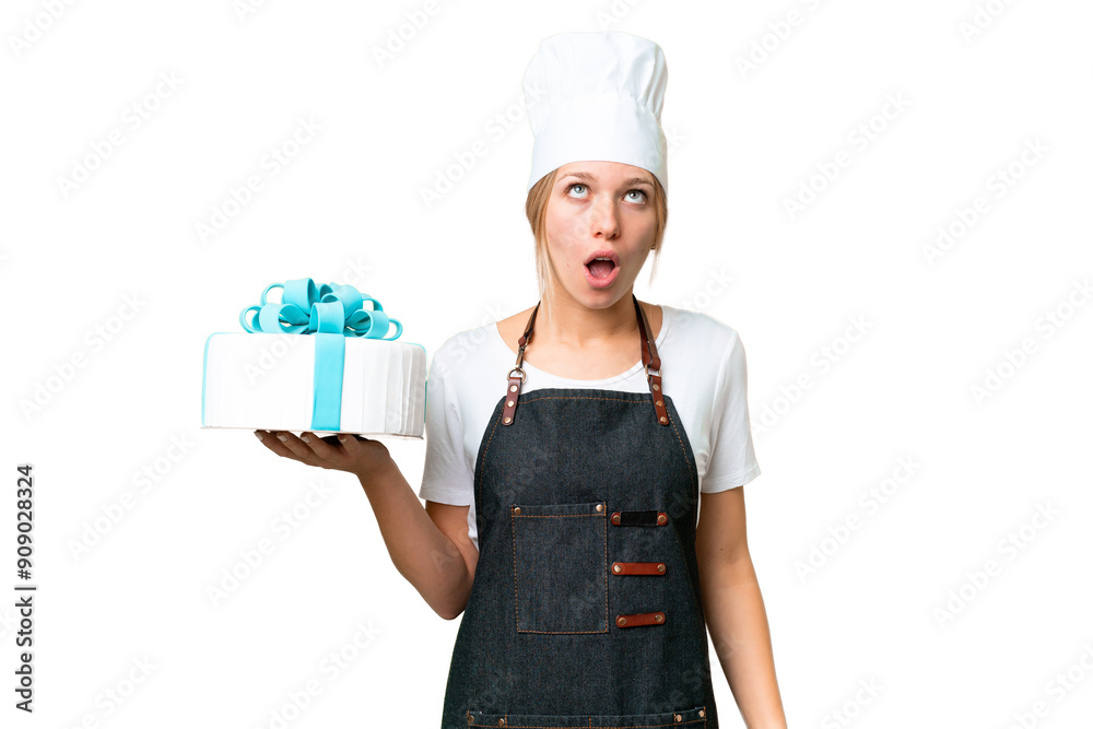 Young pastry blonde woman with a big cake over isolated chroma key background looking up and with surprised expression Young pastry blonde woman with a big cake over isolated chroma key background looking up and with surprised expression