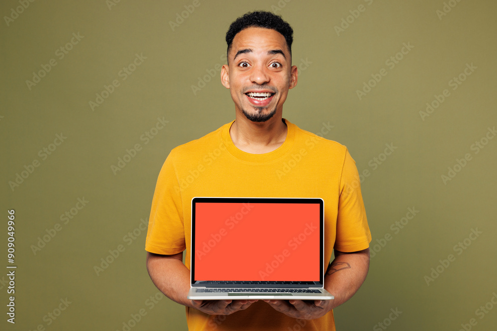 Young fun IT man of African American ethnicity he wears yellow t-shirt casual clothes hold use work on laptop pc computer isolated on plain pastel green background studio portrait. Lifestyle concept. Young fun IT man of African American ethnicity he wears yellow t-shirt casual clothes hold use work on laptop pc computer isolated on plain pastel green background studio portrait. Lifestyle concept.