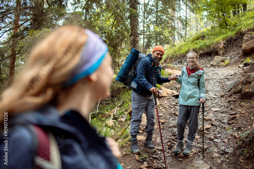 Family hiking together in forest with trekking poles photo