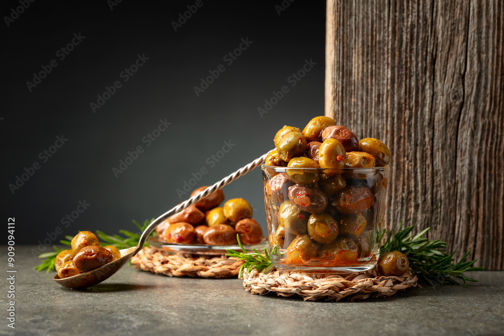 Spicy olives in a glass bowl on a stone table. Spicy olives in a glass bowl on a stone table.