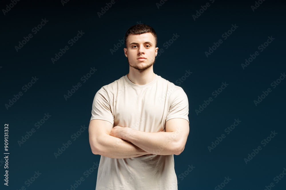 Confident athletic man crossing arms posing on blue background Confident athletic man crossing arms posing on blue background