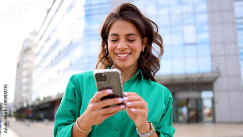 Fotografie Young woman taking a city moment to browse her smartphone