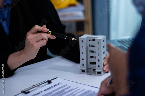 Asian female real estate agent discusses home purchase contract terms and asks clients to sign legal contract documents and insurance.