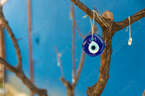 evil eye bead hanging on the tree, space for text with blue background photo