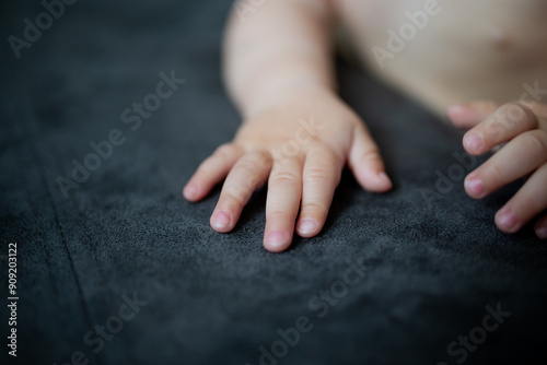 Small cute babu toddler arms on dark couch surface close up on fingers photo