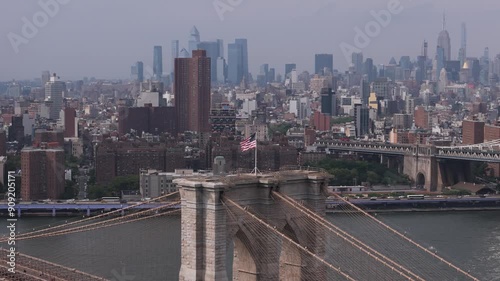 Aerial orbit shot around American flag standing on top of the Brooklyn bridge