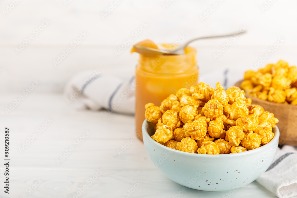 Sweet caramel popcorn in a bowl on a wooden background. Salted caramel popcorn. Caramel sauce. Close up. Topping. Place for text. Copy space Sweet caramel popcorn in a bowl on a wooden background. Salted caramel popcorn. Caramel sauce. Close up. Topping. Place for text. Copy space