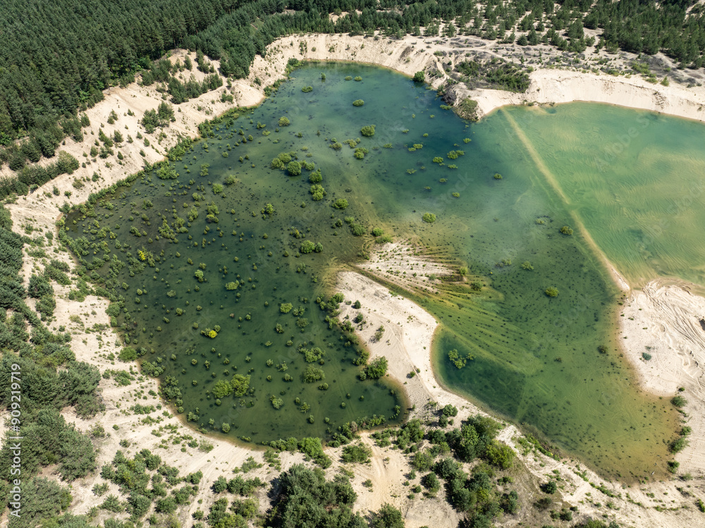 Aerial drone view of flooded sand pit. An artificial lake after a flooded sand pit. Forest submerged in a lake. Sunken sandpit with crystal clear water in Klucze, Poland. Aerial drone view of flooded sand pit. An artificial lake after a flooded sand pit. Forest submerged in a lake. Sunken sandpit with crystal clear water in Klucze, Poland.