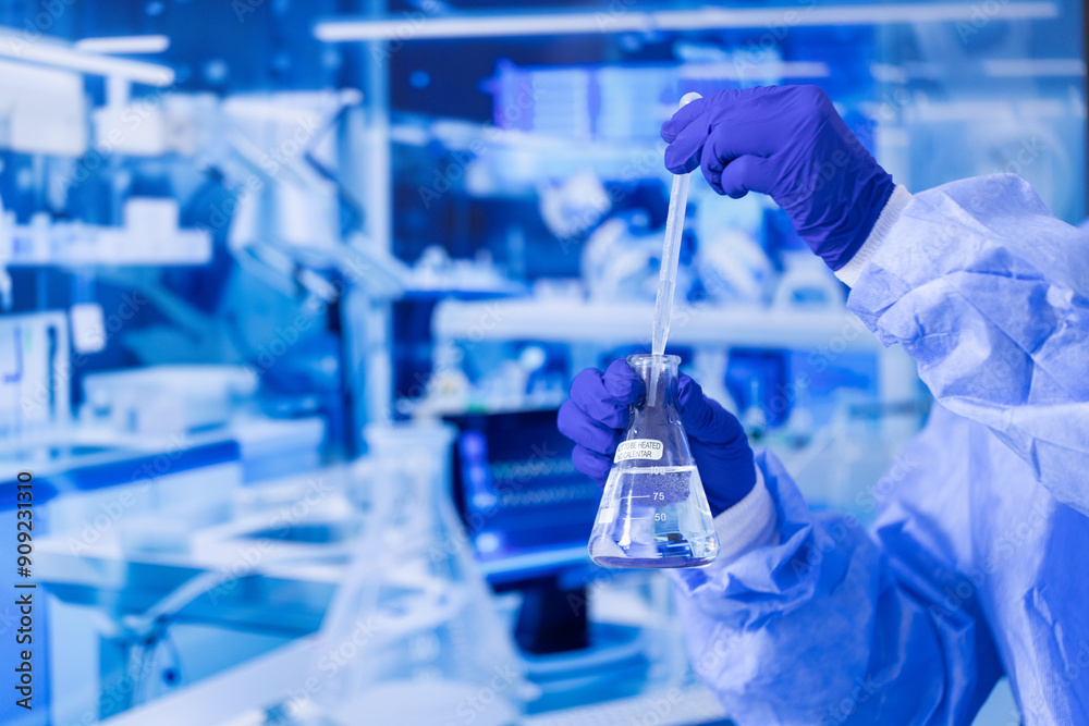 A scientist is holding a beaker with a blue liquid in it. Concept of precision and focus, as the scientist carefully measures and pours the liquid A scientist is holding a beaker with a blue liquid in it. Concept of precision and focus, as the scientist carefully measures and pours the liquid