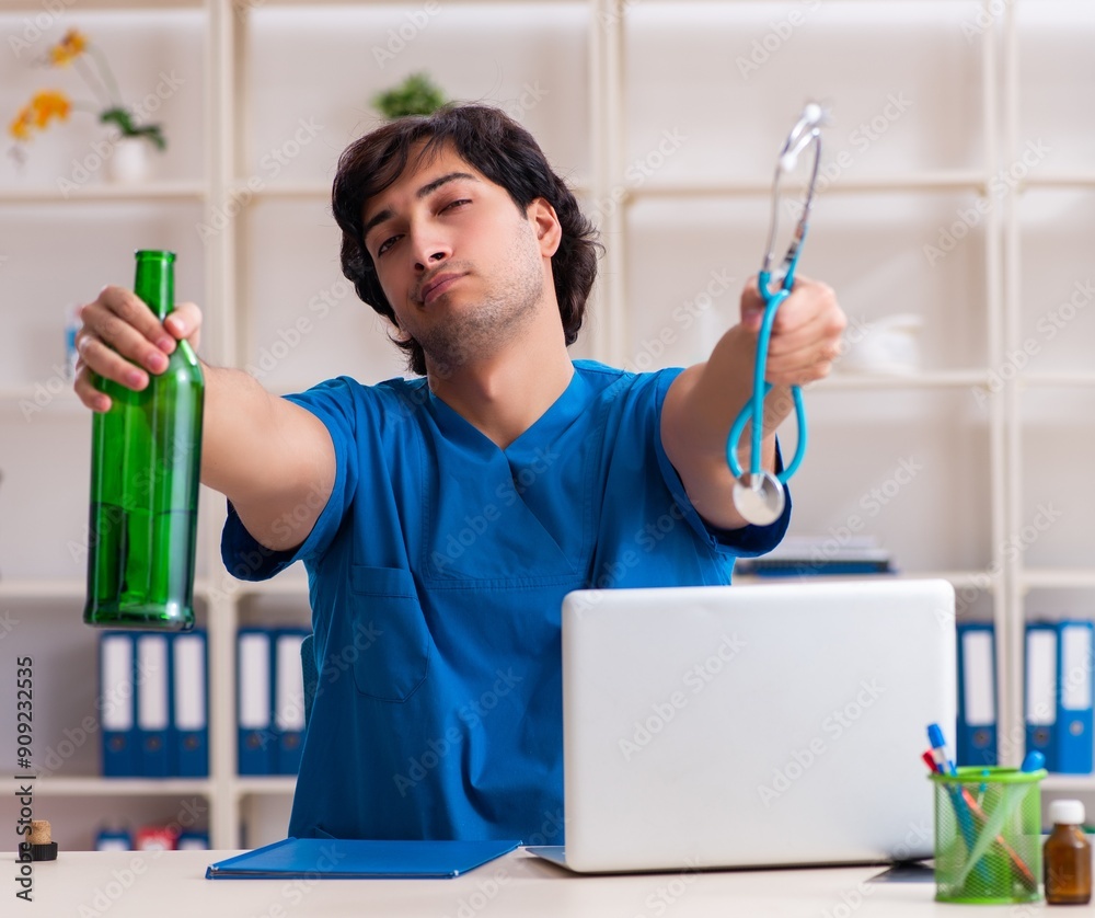 Young male doctor drinking in the office Young male doctor drinking in the office