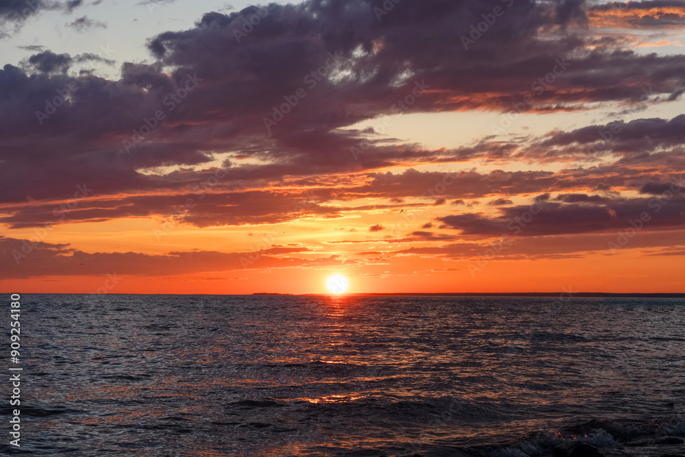 Seascape: sun setting over the horizon, reflected in the water Seascape: sun setting over the horizon, reflected in the water