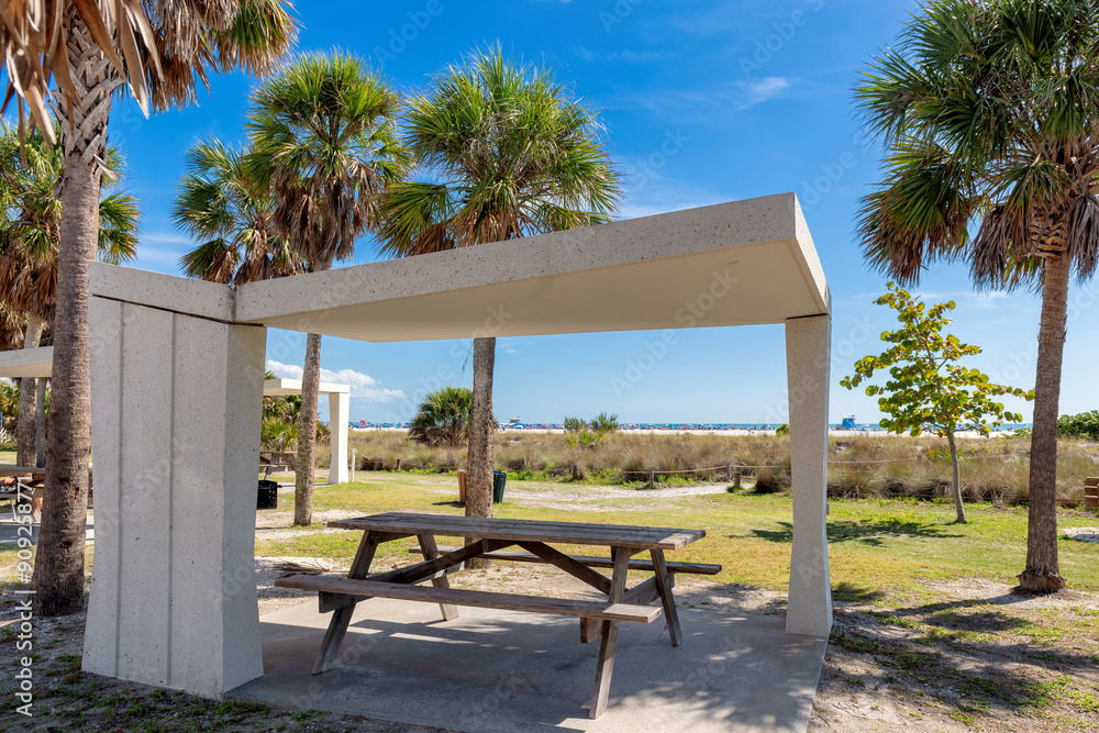 Picnic tables and shelters where visitors can enjoy a picnic under palm trees in ocean beach in the Siesta Key Beach in Florida.