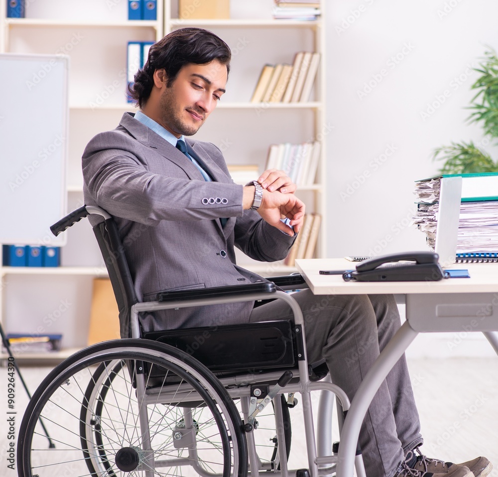 Young handsome employee in wheelchair at the office Young handsome employee in wheelchair at the office