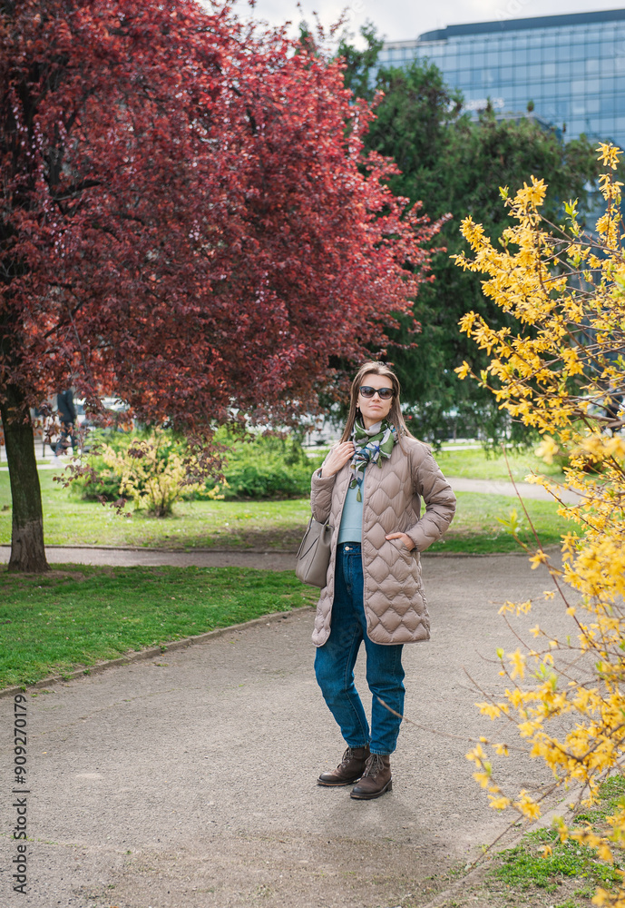 Obraz premium Beautiful stylish woman with sunglasses and bag walking in the city park