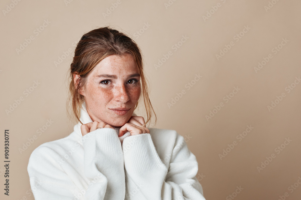 Freckled woman poses in white turtleneck sweater for fashion photoshoot in studio setting Freckled woman poses in white turtleneck sweater for fashion photoshoot in studio setting