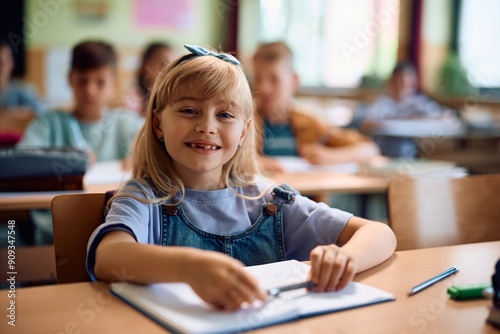 Happy schoolgirl during class in classroom looking at camera.