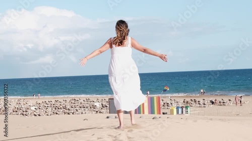 Woman walking on the dunes with a stand with LGBT flags in the background. Concept: pride, freedom
