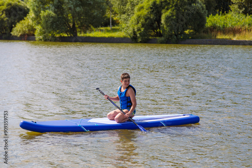 An energetic guy on a SUP board, enjoying riding the waves on a sunny day.