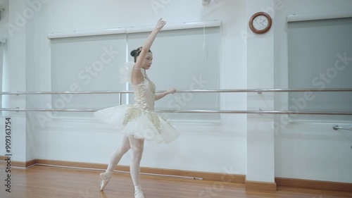 Asian Ballet dancer in full ballet clothes doing dance practice inside indoor dancing studio, holding on to the ballet handrail, Choreographer preparing for a performance. practicing moves performing
