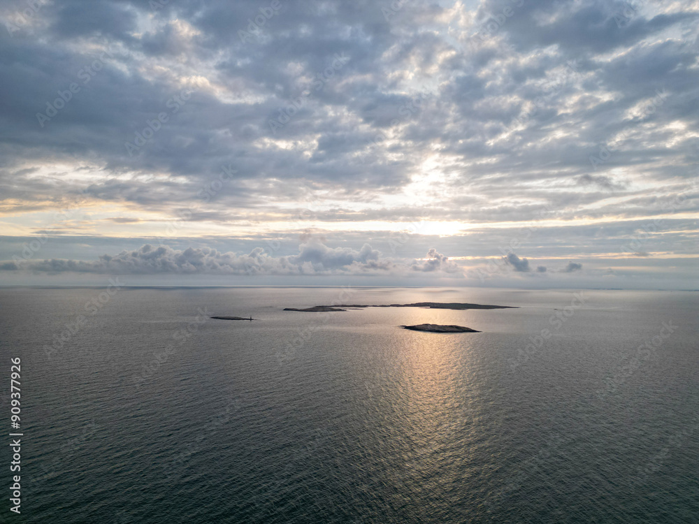 Aerial photo of sun setting over the sea and reflecting light on the still sea in Bohuslän, Sweden. Aerial photo of sun setting over the sea and reflecting light on the still sea in Bohuslän, Sweden.