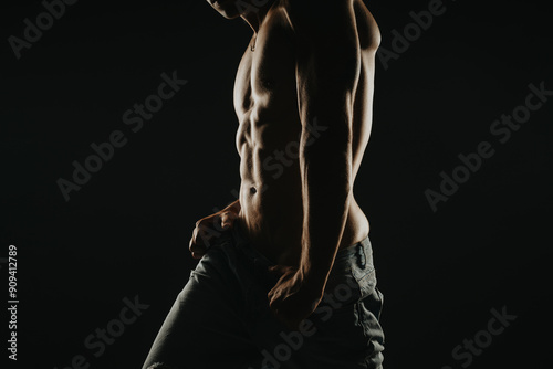 Muscular man with a well-defined torso captured in dramatic lighting, emphasizing fitness, strength, and dedication to physical training.