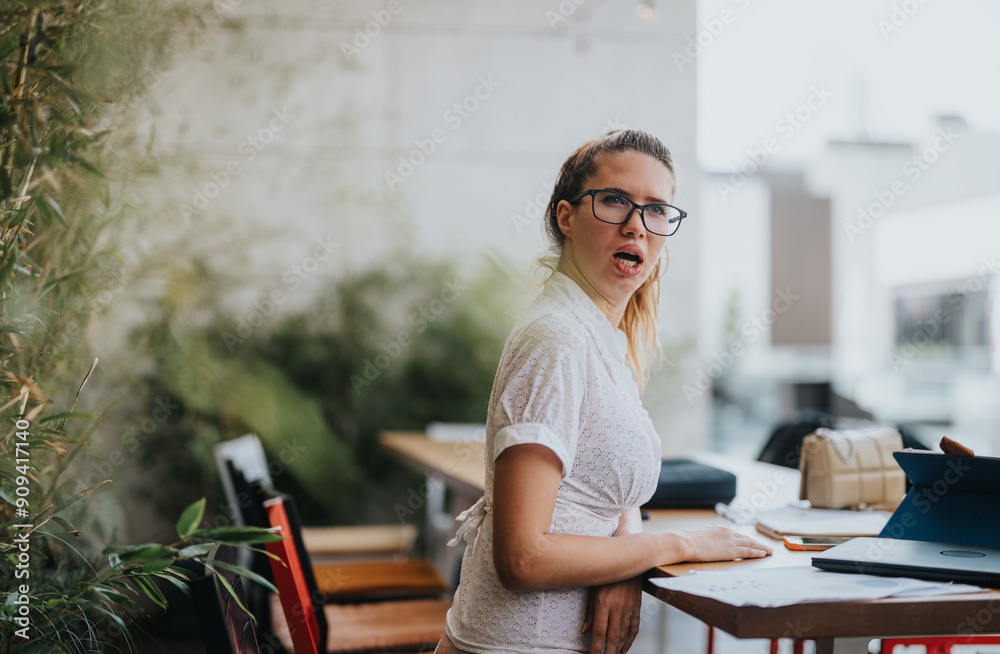 Young businesswoman with glasses, working on a project and making an expressive face in a modern office environment. Young businesswoman with glasses, working on a project and making an expressive face in a modern office environment.