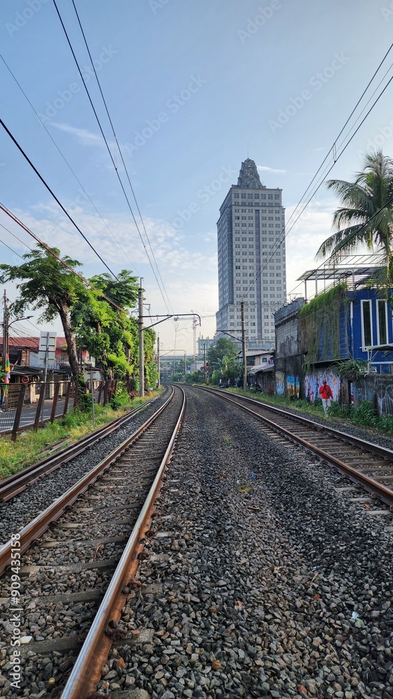 Fototapeta premium A picturesque rail road landscape in Indonesia, featuring lush greenery, rolling hills, and vibrant skies. The scenic view captures the natural beauty and tranquil charm of the Indonesian countryside.