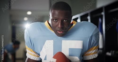 Football, black man and energy with ball in locker room for match, game prep or adrenaline for tournament. Player, professional athlete or sports portrait with determination and ready for competition photo