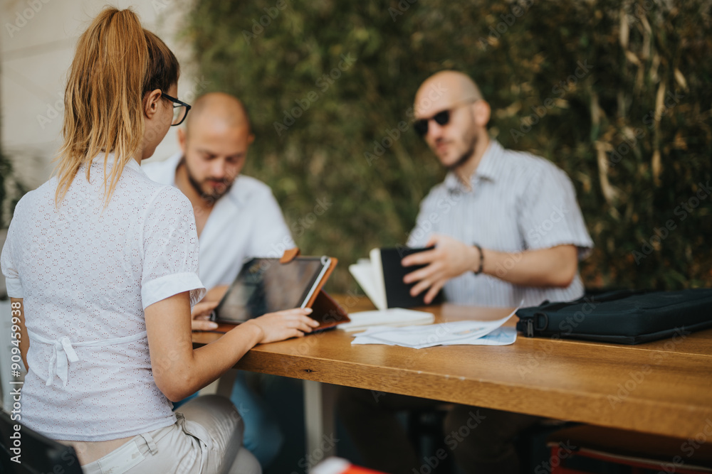 Team of colleagues having a casual business meeting outdoors, discussing work, and using a tablet. Team of colleagues having a casual business meeting outdoors, discussing work, and using a tablet.
