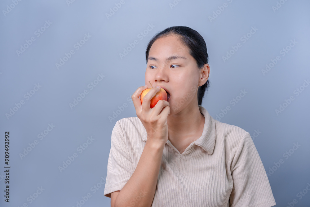 Close-up of a happy Asian woman eating an apple in her hand, enjoying the vitamin-rich fruit. Organic fruit. Healthy food. Healthy living. Vegetarian with lifestyle concept. Close-up of a happy Asian woman eating an apple in her hand, enjoying the vitamin-rich fruit. Organic fruit. Healthy food. Healthy living. Vegetarian with lifestyle concept.