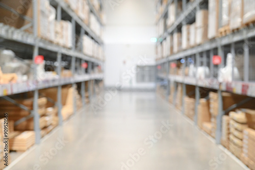 Blurry perspective of a large warehouse aisle with shelves stacked with boxes and goods.