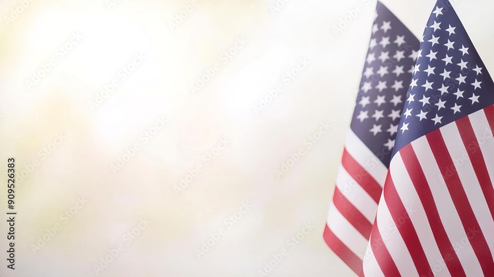 Fototapeta premium Two American flags waving in the wind against a bright, blurred background.
