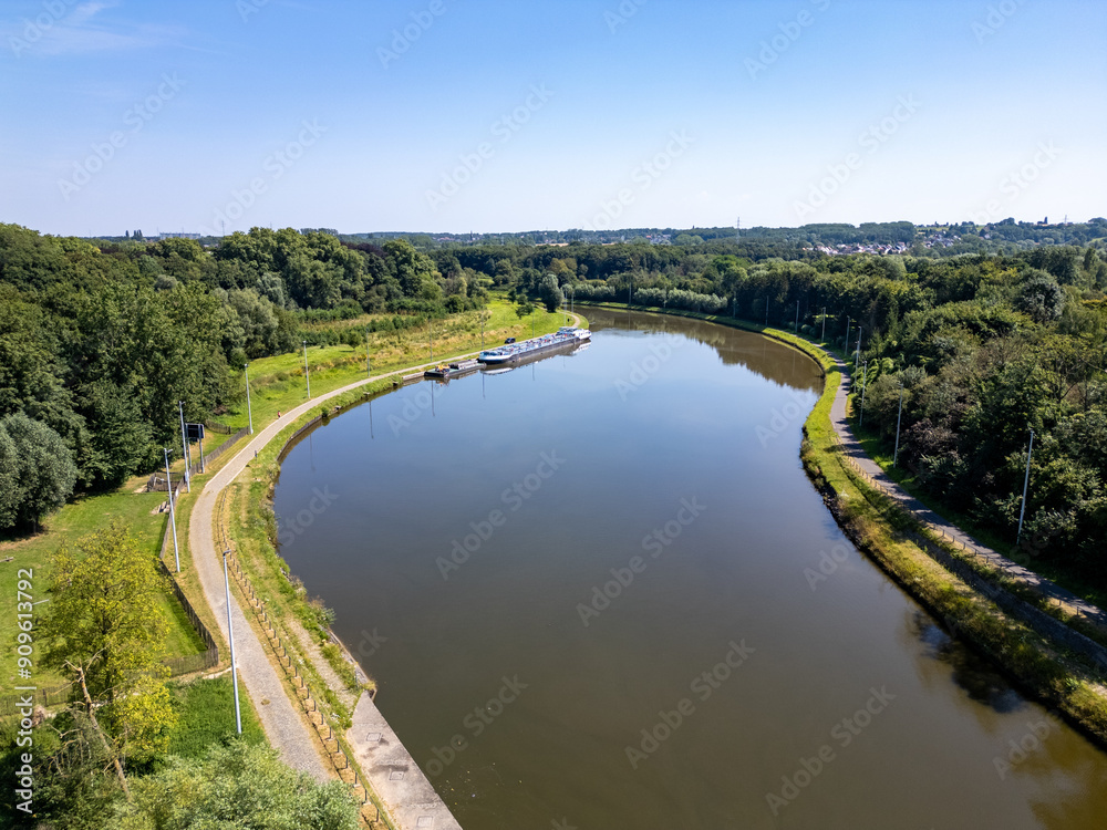 An aerial view captures a river elegantly curving through vibrant greenery beneath a clear blue sky above An aerial view captures a river elegantly curving through vibrant greenery beneath a clear blue sky above
