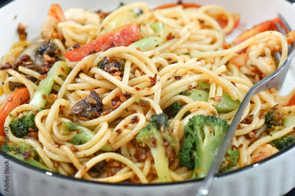 Stir-fried pasta with prawn, broccoli, mushroom and tomato. Served on a white plate. Stir-fried pasta with prawn, broccoli, mushroom and tomato. Served on a white plate.