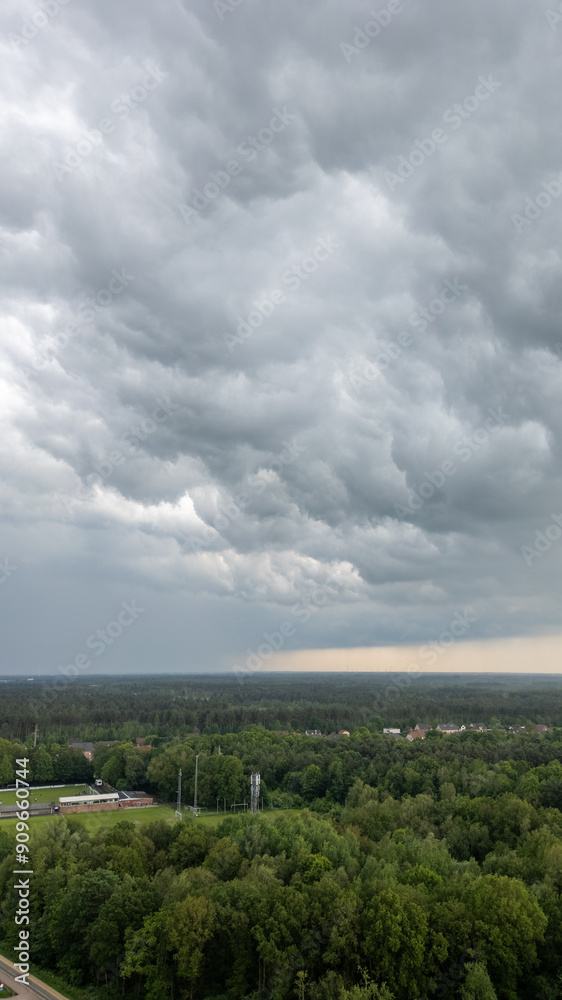 Fototapeta premium A breathtaking aerial view depicts dark clouds looming ominously over lush, verdant forests and distant horizons