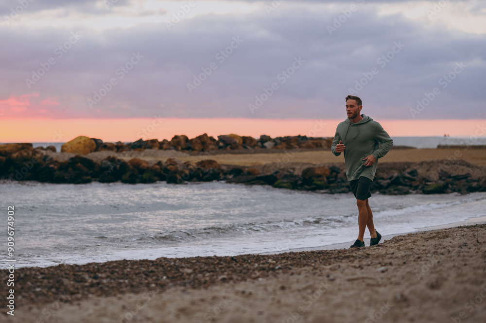 Full body profile young strong sporty athletic toned fit sportsman man wear sports clothes run jogging warm up train at sunrise sun dawn over sea sand beach outdoor on seaside in summer day morning Full body profile young strong sporty athletic toned fit sportsman man wear sports clothes run jogging warm up train at sunrise sun dawn over sea sand beach outdoor on seaside in summer day morning