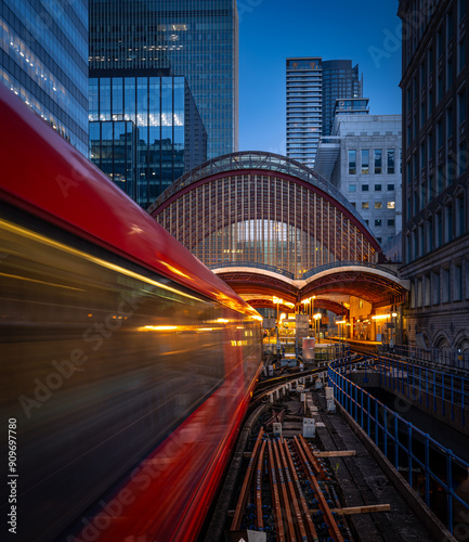 A vibrant red London underground subway train is traveling through bustling city during night hours