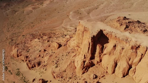 The Flaming Cliffs in the Gobi Desert, Mongolia, under a clear blue sky, showcasing its iconic red sandstone formations and barren landscape.