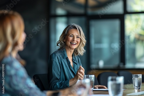 A smiling middle-aged Caucasian woman engaged in a meeting, showcasing a warm and approachable demeanor.