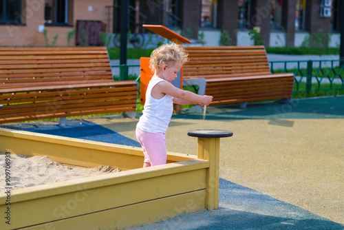 Child playing in the sandbox in the playground in the courtyard of a house