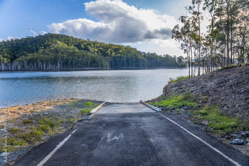 Φωτογραφία A boat ramp into a lake with forested hills and a blue sky with cumulus clouds in the background in a diminishing perspective photo of a peaceful scene at Hinze dam on the Gold Coast in Australia