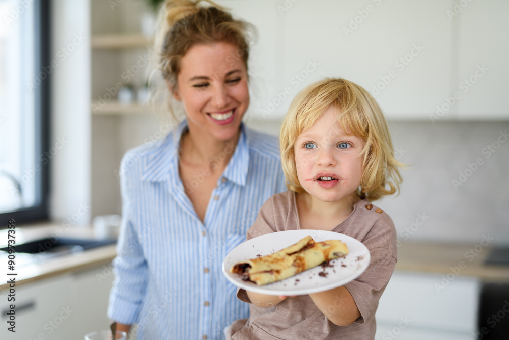 Mom and son eating pancakes together, morning in the kitchen for singel mother. Parents and children spending weekend day indoors. Mom and son eating pancakes together, morning in the kitchen for singel mother. Parents and children spending weekend day indoors.
