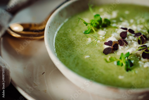 Delicios green soup decorated with micro vegetable on a wooden table. 