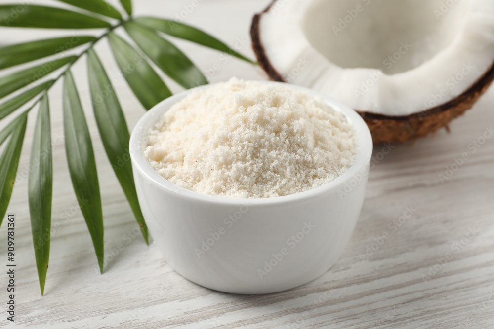 Fresh coconut flour in bowl, nut and palm leaf on white wooden table, closeup Fresh coconut flour in bowl, nut and palm leaf on white wooden table, closeup