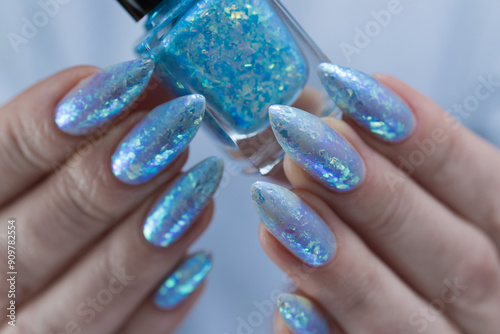 Female hand with long nails and bright light blue and silver manicure	 photo